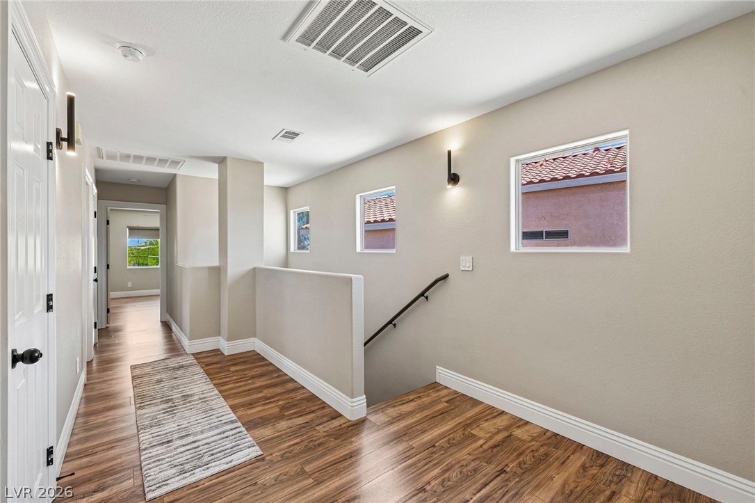 1176 Butternut Ranch Court Henderson, NV 89052 - Photo 19 of 60 Natural wood-tone flooring defines this inviting hallway, guiding visitors through the home's upper level.
