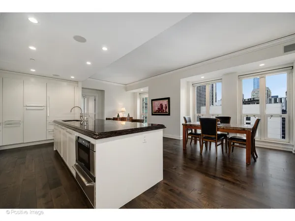 a kitchen with stainless steel appliances kitchen island granite countertop a stove top oven a sink a dining table and chairs