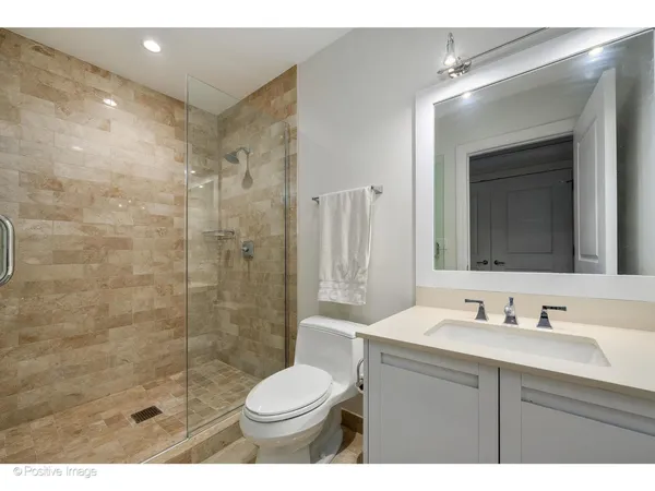 a bathroom with a shower sink vanity mirror and toilet