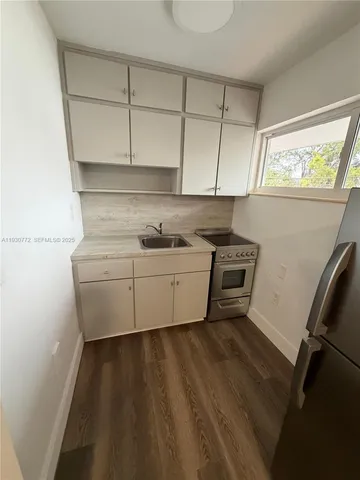 a kitchen with a sink a stove cabinets and a window
