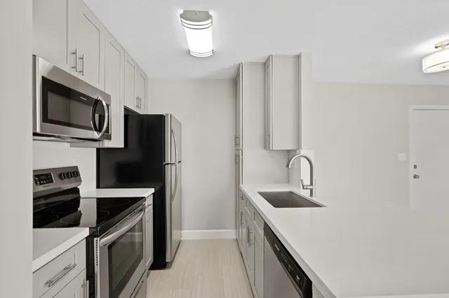 an empty room with chandelier fan and windows