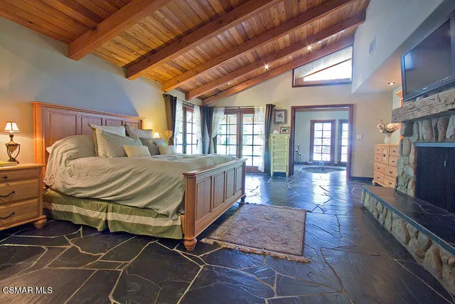 a bedroom with a balcony a bed and a dresser in it