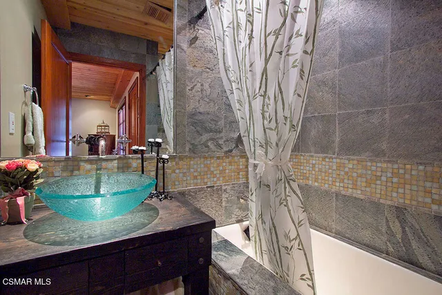 a bathroom with a granite countertop sink a mirror and shower