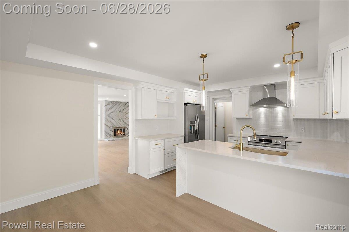 1447 Ravineview Court, Unit C12 Bloomfield Hills, MI 48304 - Photo 22 of 49 Contemporary kitchen featuring a white island with a built-in sink, gold-toned faucet, and pendant lighting
