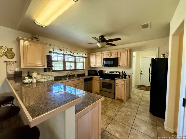 a kitchen with a sink a counter top space appliances and cabinets