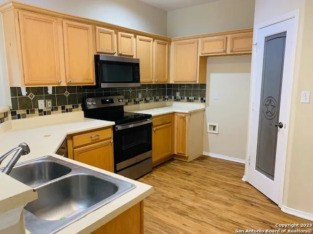 a kitchen with stainless steel appliances wooden cabinets a sink and a refrigerator