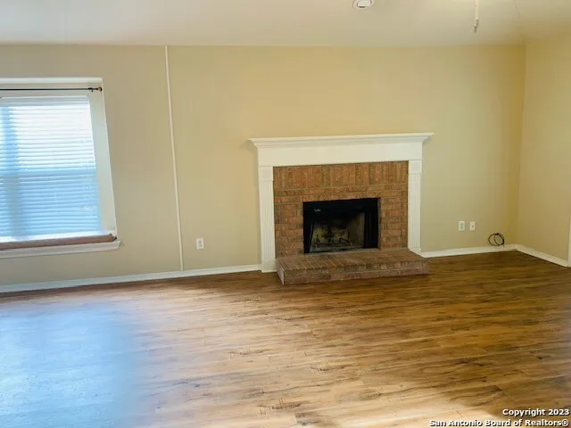 a view of an empty room with wooden floor and a fireplace