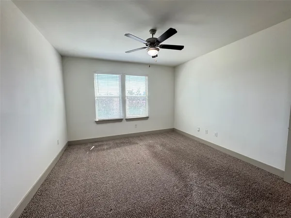 an empty room with a window and a fan