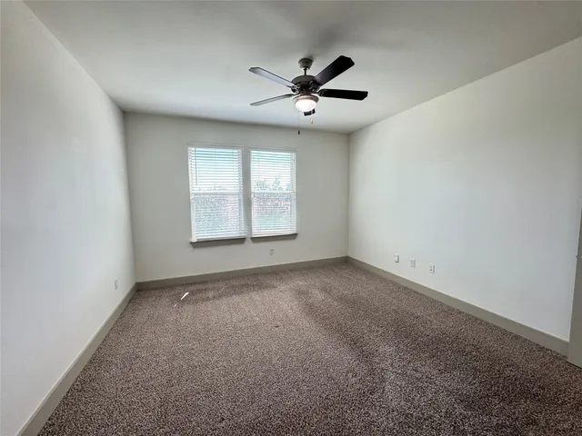 an empty room with a window and a fan