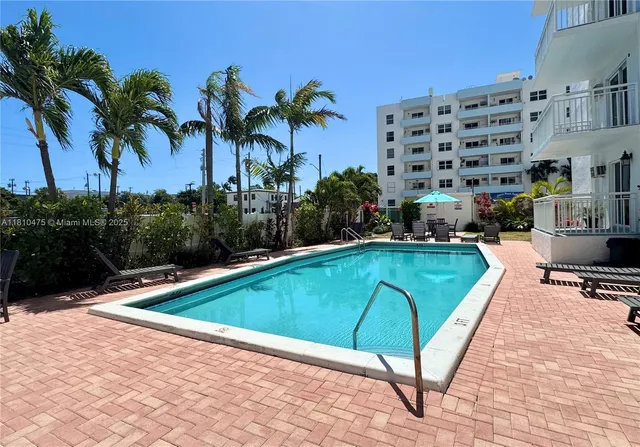 a small pool with lawn chairs and potted plants