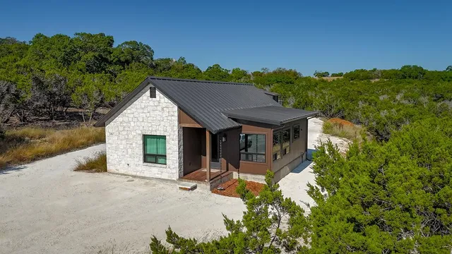 a kitchen with stainless steel appliances granite countertop a stove a refrigerator a kitchen island a table and chairs with wooden floor