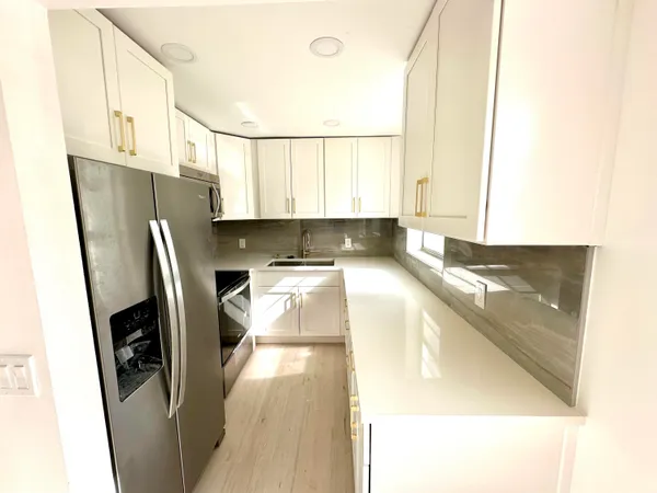 a kitchen with stainless steel appliances granite countertop a refrigerator a sink and a stove