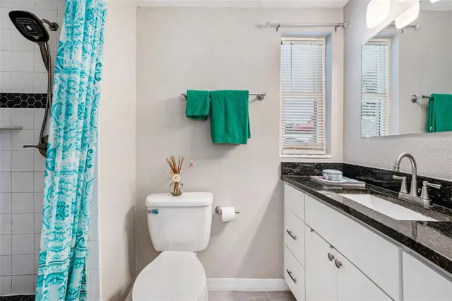 a bathroom with a granite countertop sink toilet and mirror