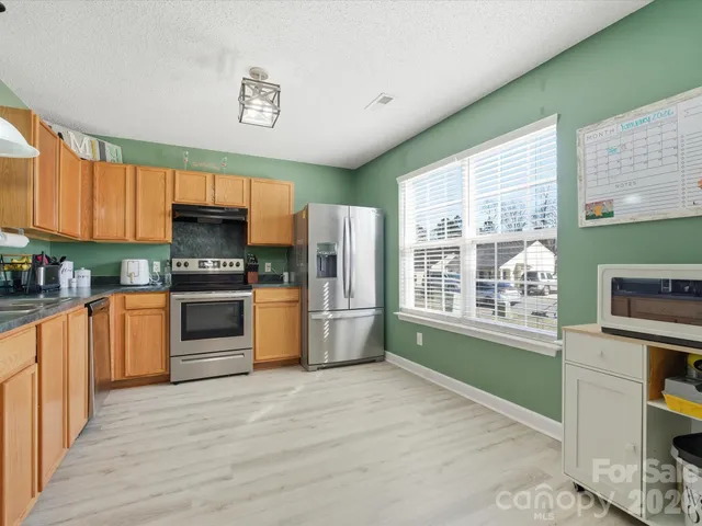 a kitchen with granite countertop a stove a sink and a refrigerator