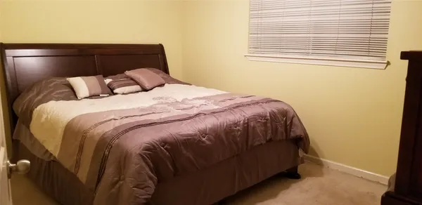 a bed sitting in a bedroom next to a window and a wooden floor