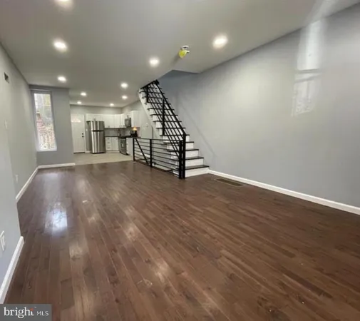 a view of an empty room with wooden floor and stairs