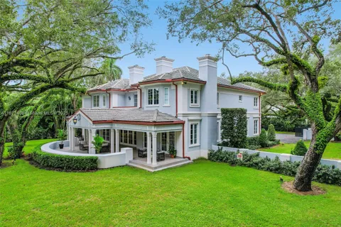 a front view of a house with garden and trees