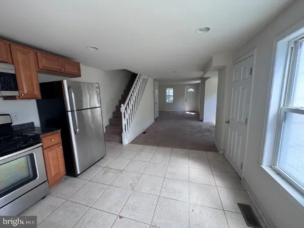 a view of a refrigerator in kitchen and empty room