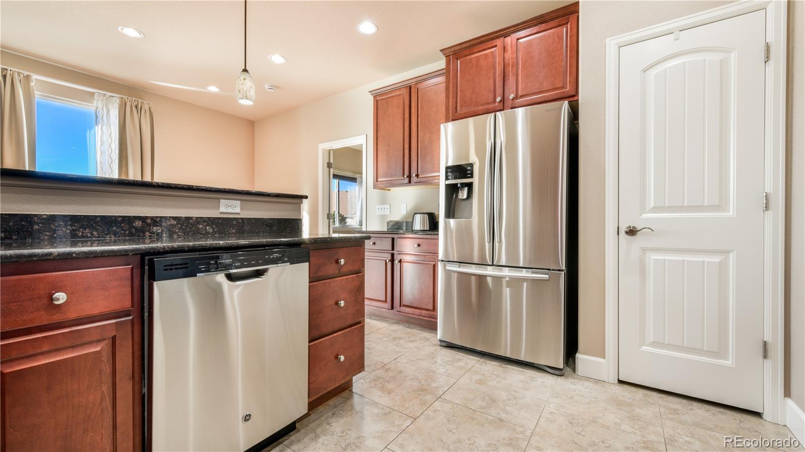 10484 Mile Post Loop Fountain, CO 80817 - Photo 13 of 50 a kitchen with stainless steel appliances granite countertop a refrigerator a sink a stove and white cabinets with wooden floor
