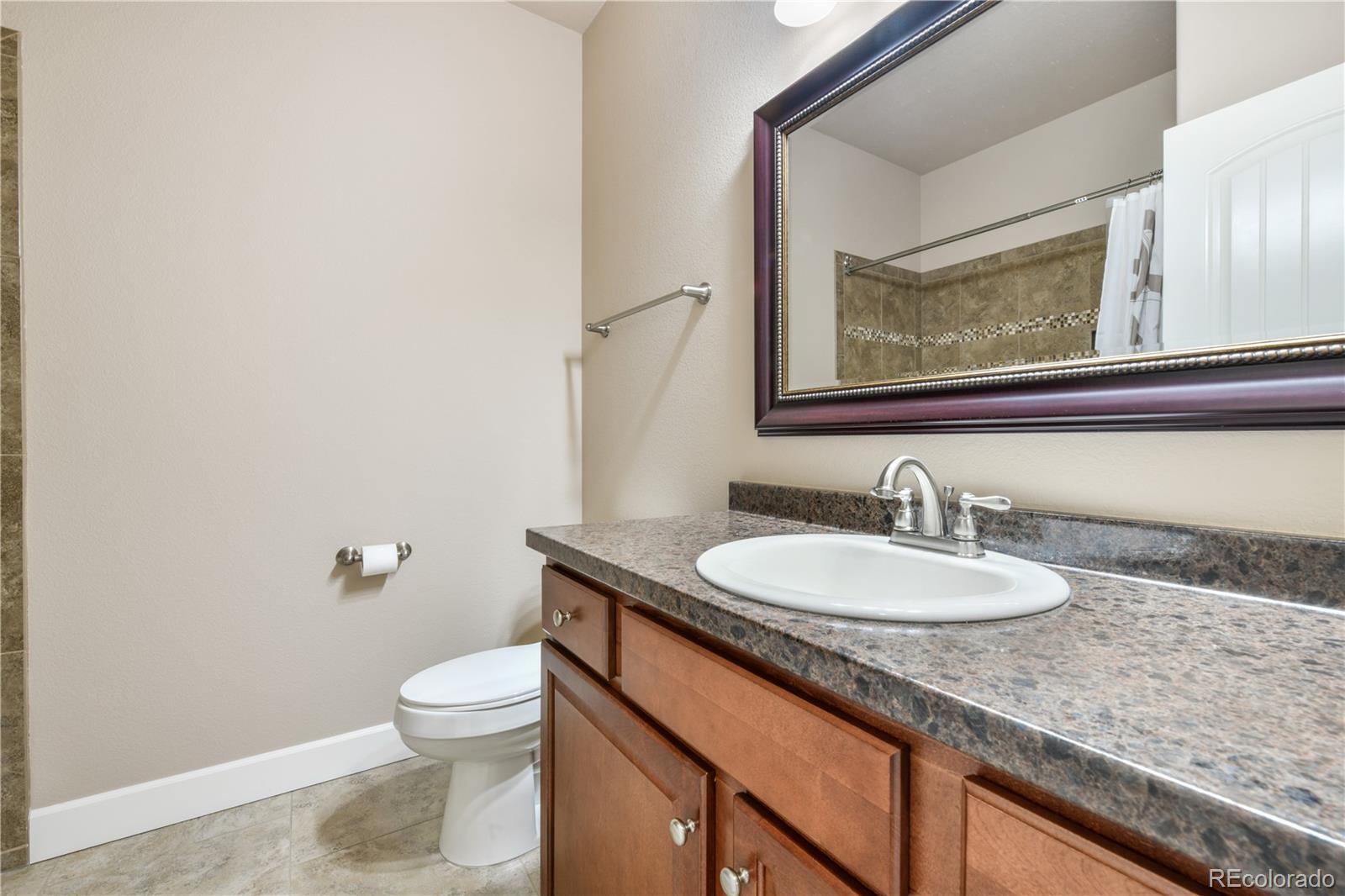 10484 Mile Post Loop Fountain, CO 80817 - Photo 29 of 50 a bathroom with a granite countertop toilet a sink and mirror
