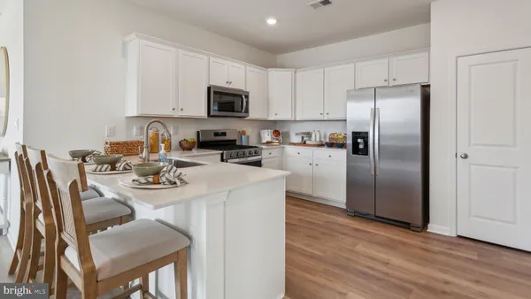 a kitchen with stainless steel appliances granite countertop a microwave a stove a sink dishwasher a refrigerator with a dining table and chairs