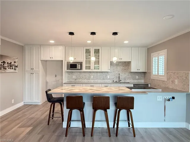 a kitchen with stainless steel appliances granite countertop a table chairs sink refrigerator and cabinets