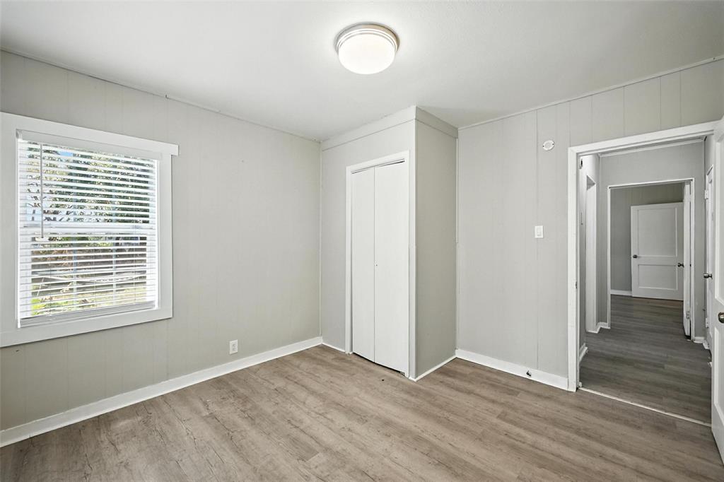 204 Graham Avenue Bonham, TX 75418 - Photo 9 of 21 Unfurnished bedroom featuring wooden walls, light wood-style flooring, and a closet
