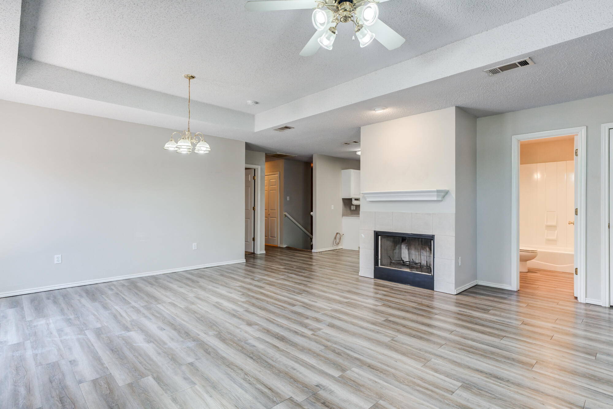 3425 97th Street Lubbock, TX 79423 - Photo 2 of 22 an empty room with wooden floor fireplace and windows