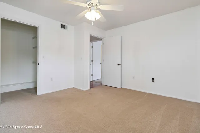 an empty room with a chandelier fan and closet area