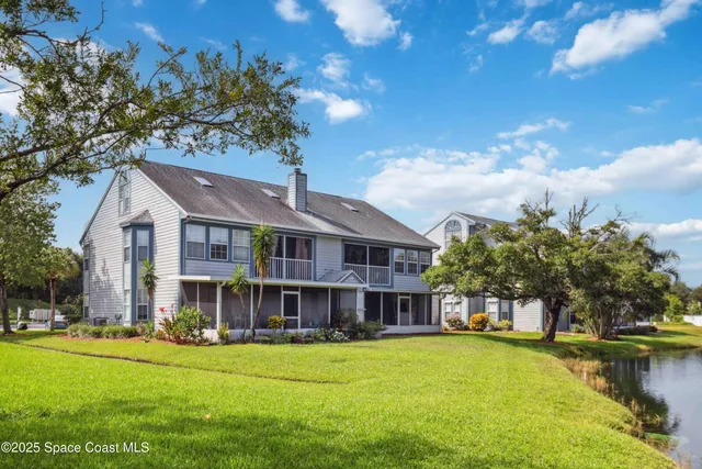 a view of a big house with a big yard and large trees