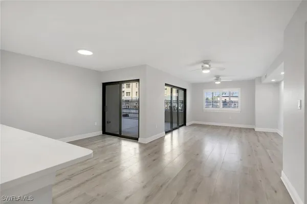 a view of an empty room with window and wooden floor