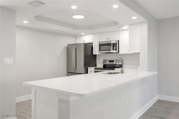 a kitchen with kitchen island a refrigerator sink microwave and cabinets