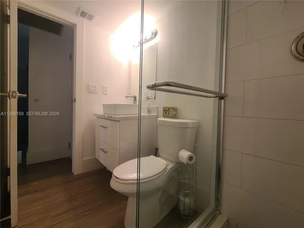 a bathroom with a granite countertop toilet a sink a mirror and shower
