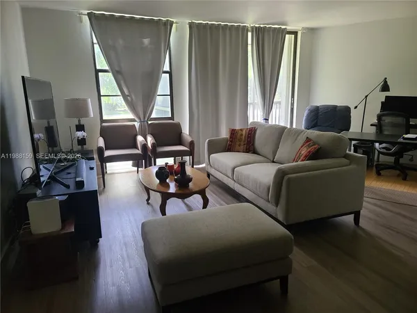 a living room with furniture a large window and wooden floor