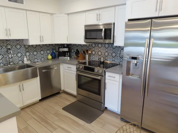 a kitchen with stainless steel appliances kitchen island granite countertop a refrigerator stove and sink