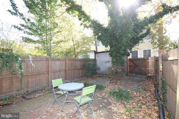 a view of a backyard with table and chairs potted plants and large tree