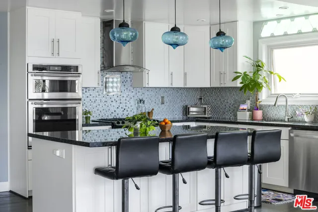 a kitchen with stainless steel appliances kitchen island granite countertop a table and chairs in it