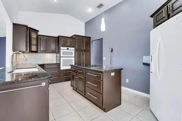 a kitchen with stainless steel appliances granite countertop a refrigerator and a stove