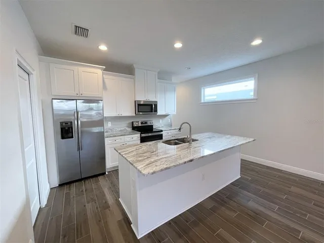 a kitchen with a sink a refrigerator a microwave and cabinets