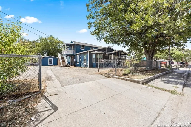 a view of a white house with a large tree