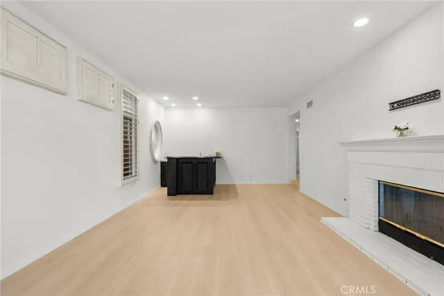 an empty room with windows cabinet and fireplace