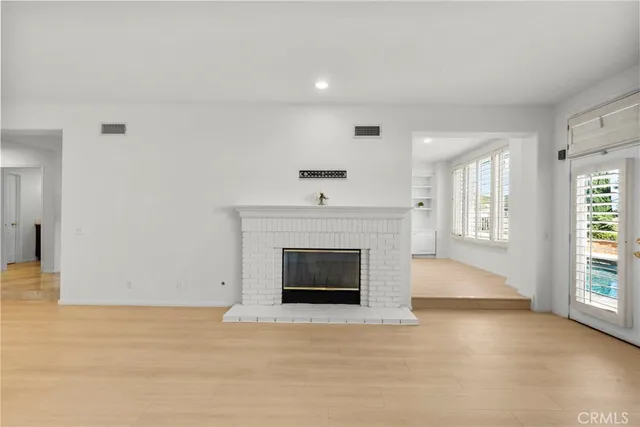 an empty room with windows and fireplace