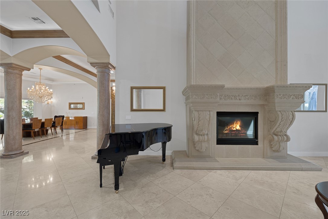 1545 Villa Rica Drive Henderson, NV 89052 - Photo 12 of 61 Living area featuring decorative columns, arched walkways, a high end fireplace, ornamental molding, and a towering ceiling