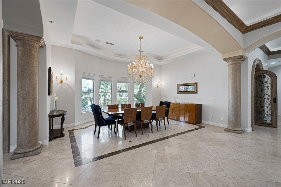 1545 Villa Rica Drive Henderson, NV 89052 - Photo 14 of 61 Dining area featuring ornate columns, a raised ceiling, inlaid floor details, crown molding, and arched walkways