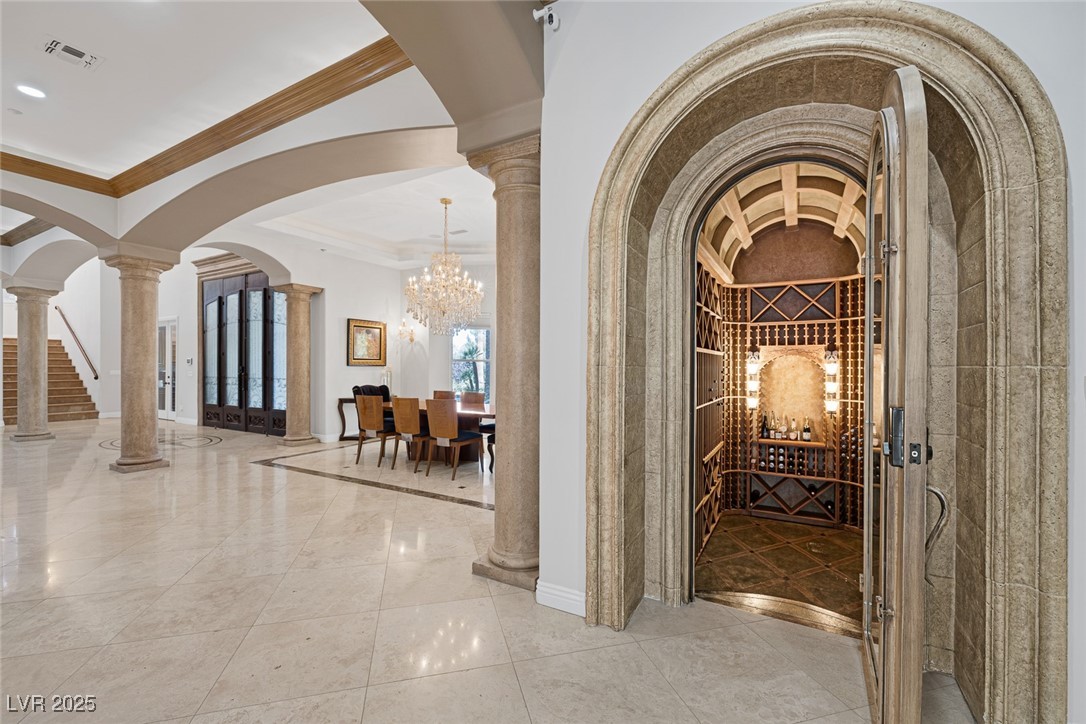 1545 Villa Rica Drive Henderson, NV 89052 - Photo 15 of 61 Wine area featuring arched walkways, ornate columns, a chandelier, crown molding, and tile patterned flooring