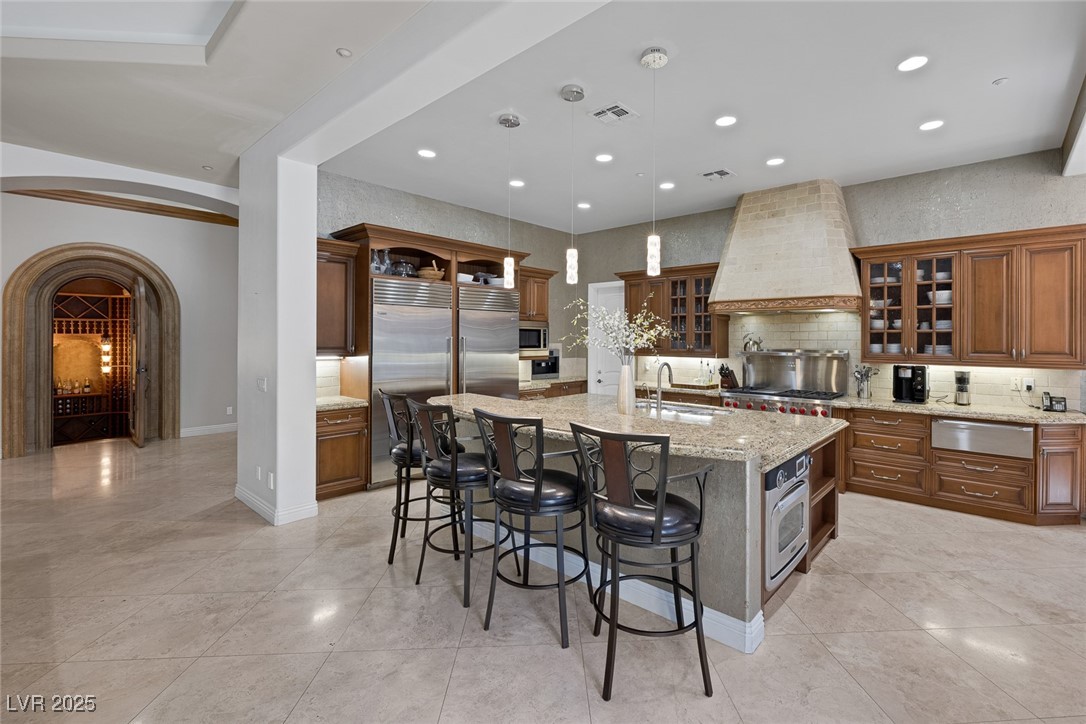 1545 Villa Rica Drive Henderson, NV 89052 - Photo 17 of 61 Kitchen with arched walkways, open shelves, decorative backsplash, appliances with stainless steel finishes, and a kitchen bar
