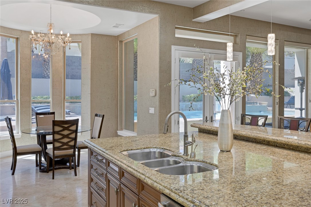 1545 Villa Rica Drive Henderson, NV 89052 - Photo 22 of 61 Kitchen featuring a chandelier, light stone countertops, pendant lighting, and brown cabinetry