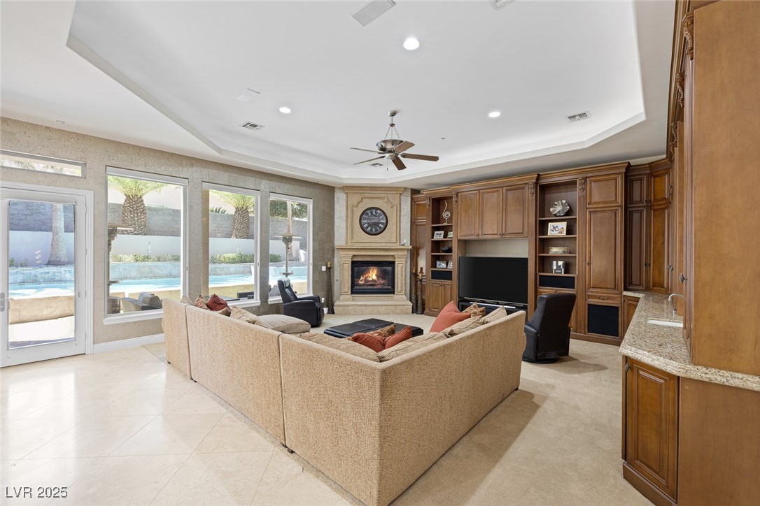 1545 Villa Rica Drive Henderson, NV 89052 - Photo 24 of 61 Living room with a glass covered fireplace, a raised ceiling, recessed lighting, and a ceiling fan