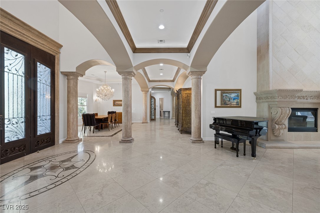 1545 Villa Rica Drive Henderson, NV 89052 - Photo 9 of 61 Entryway with crown molding, arched walkways, decorative columns, a chandelier, and a high ceiling