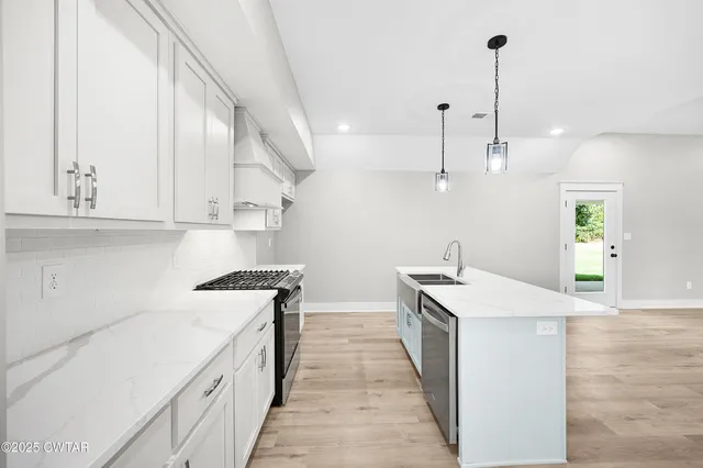 a kitchen with stainless steel appliances granite countertop a sink a stove and a wooden floors
